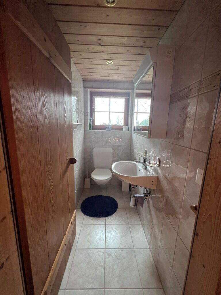 Une petite salle de bain avec des toilettes, un lavabo et des murs en bois.