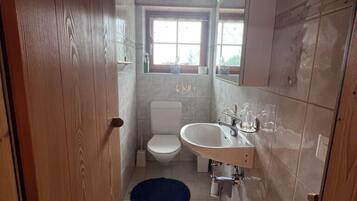 Une petite salle de bain avec des toilettes, un lavabo et des murs en bois.