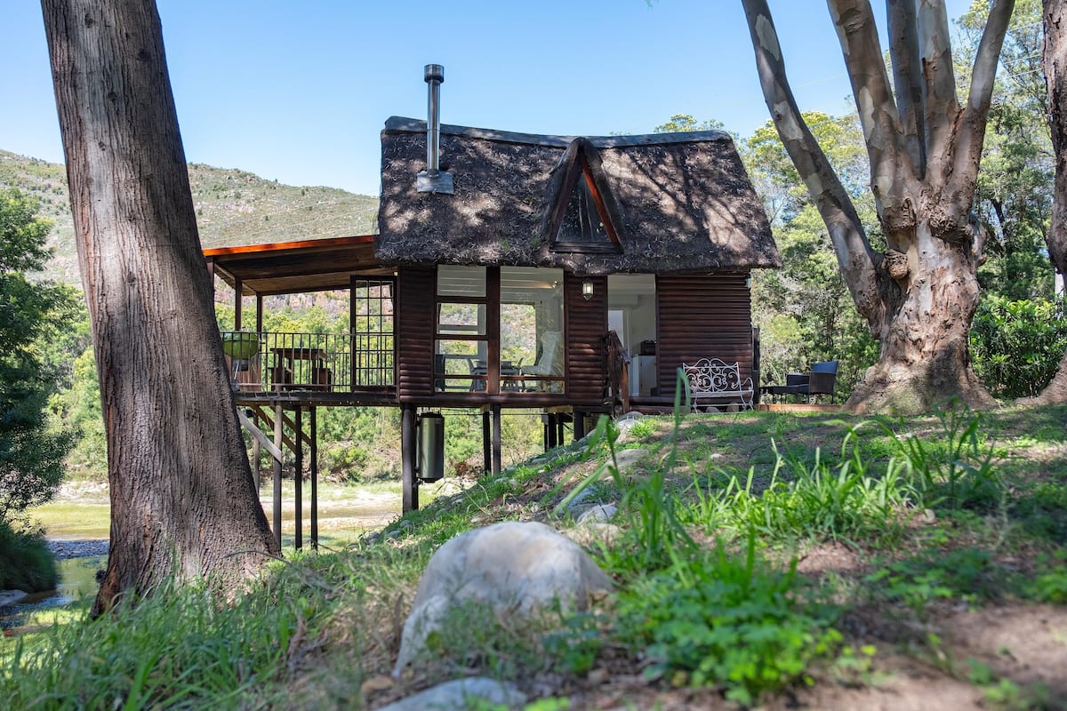 Een houten vakantiehuis met balkon, omringd door bomen en een natuurlandschap.