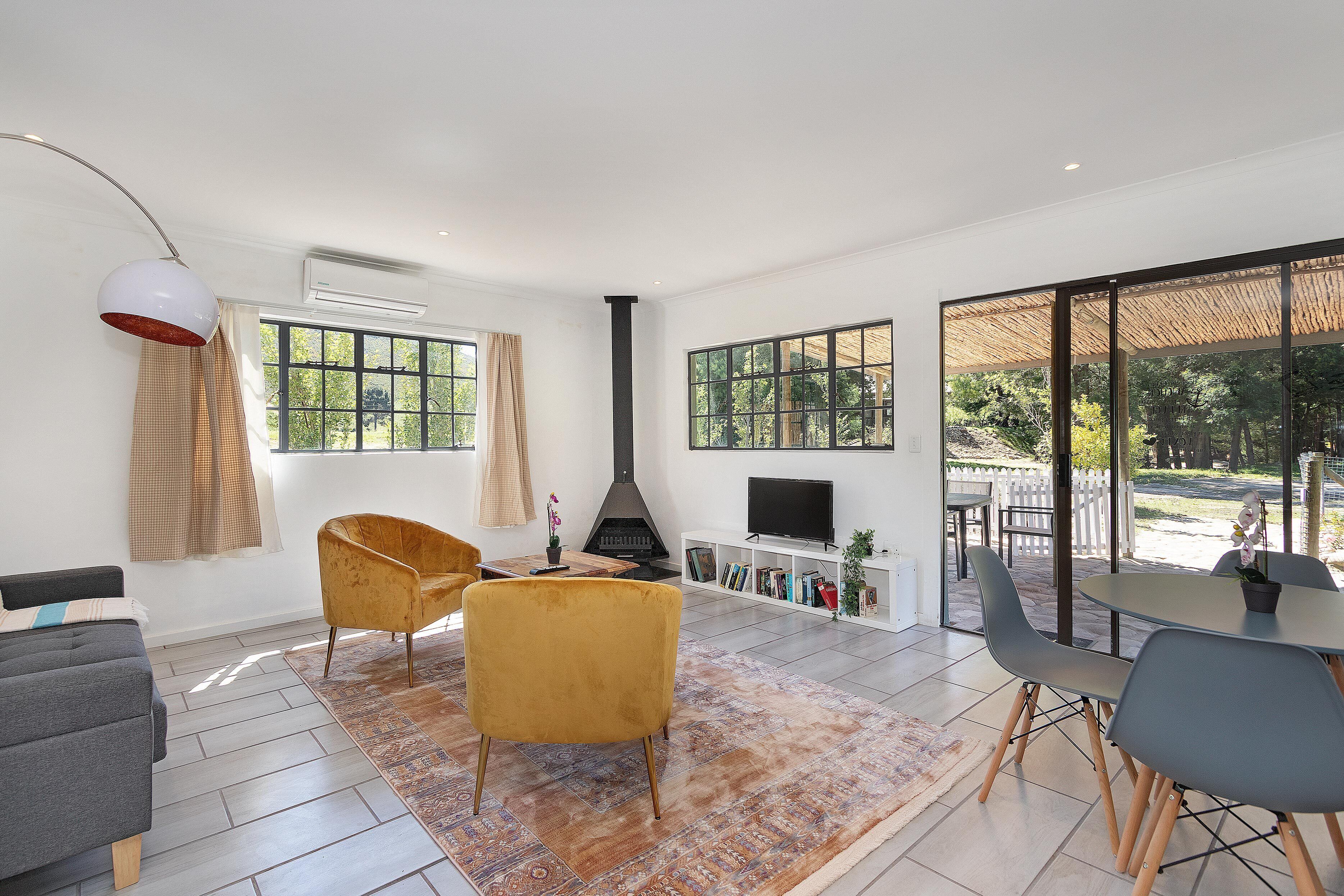 A modern living room with a sofa, armchair, TV stand, and a fireplace.