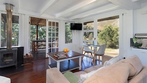 A spacious living area with a fireplace, a comfortable sofa, a wooden coffee table, and a television. - La Ferme Guest Farm (Franschhoek)