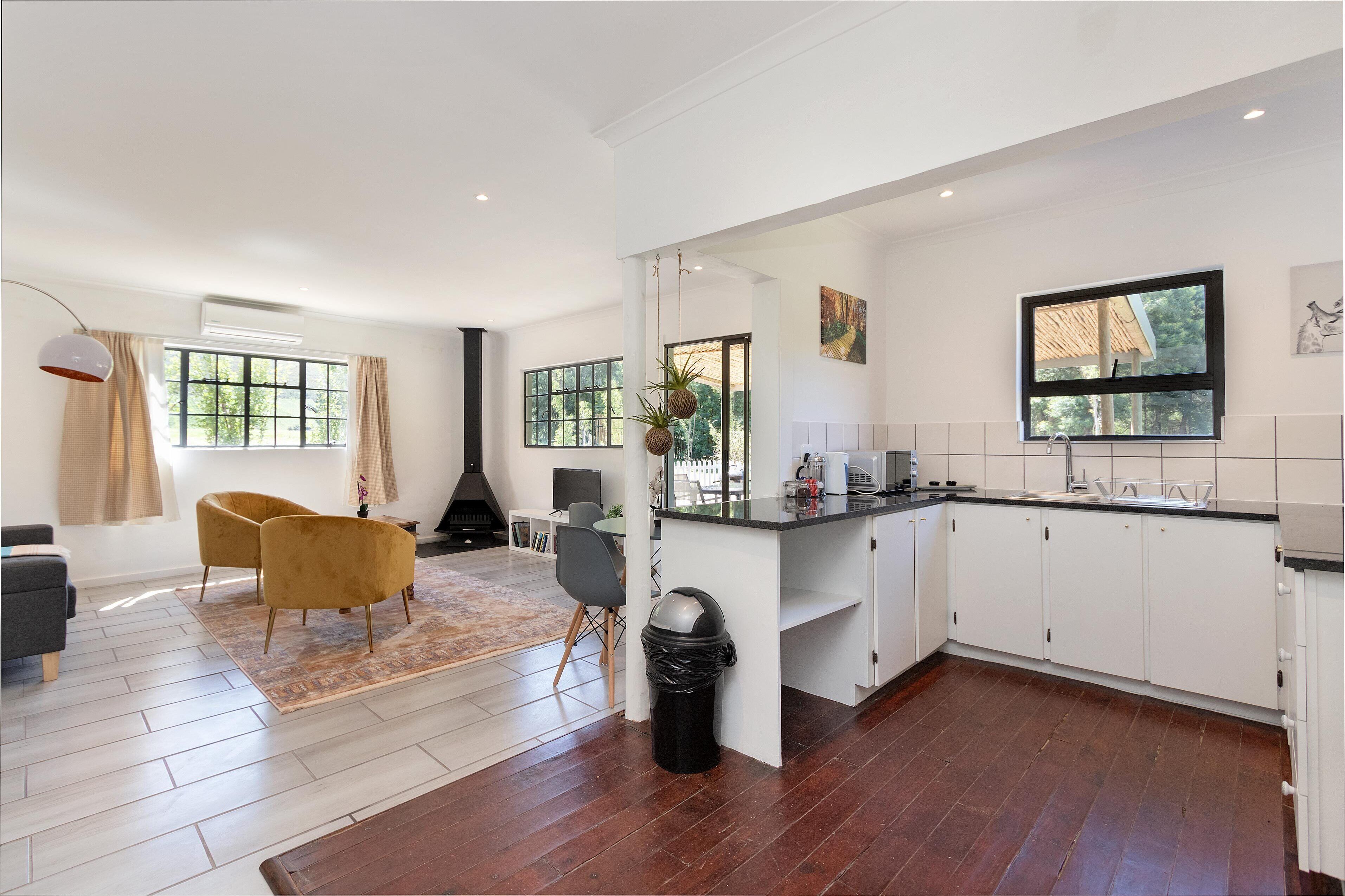 A modern kitchen with white cabinets, a black countertop, and a large window.