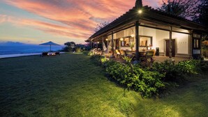 A house with a covered patio, a dining area, and a view of the ocean at dusk. - Bali Amori Vista (Cemagi)