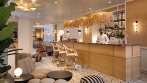 A bar area with a wooden counter, bar stools, and a seating area with sofas and round tables. - Le Clark Hotel (Paris)
