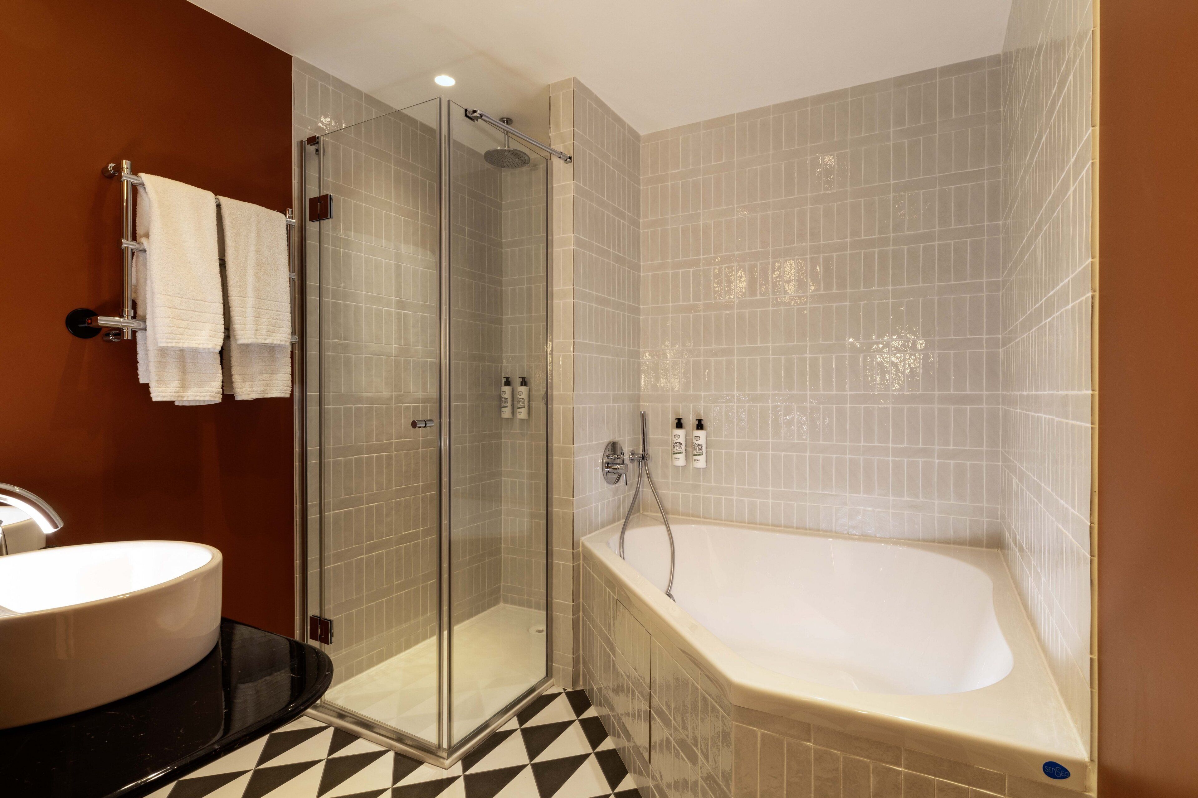 Een moderne badkamer met een douchecabine, een vrijstaand bad en een rond wastafel.