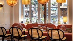 A cozy interior with a red sofa, wicker chairs, and hanging lamps. - Le Clark Hotel (Paris)