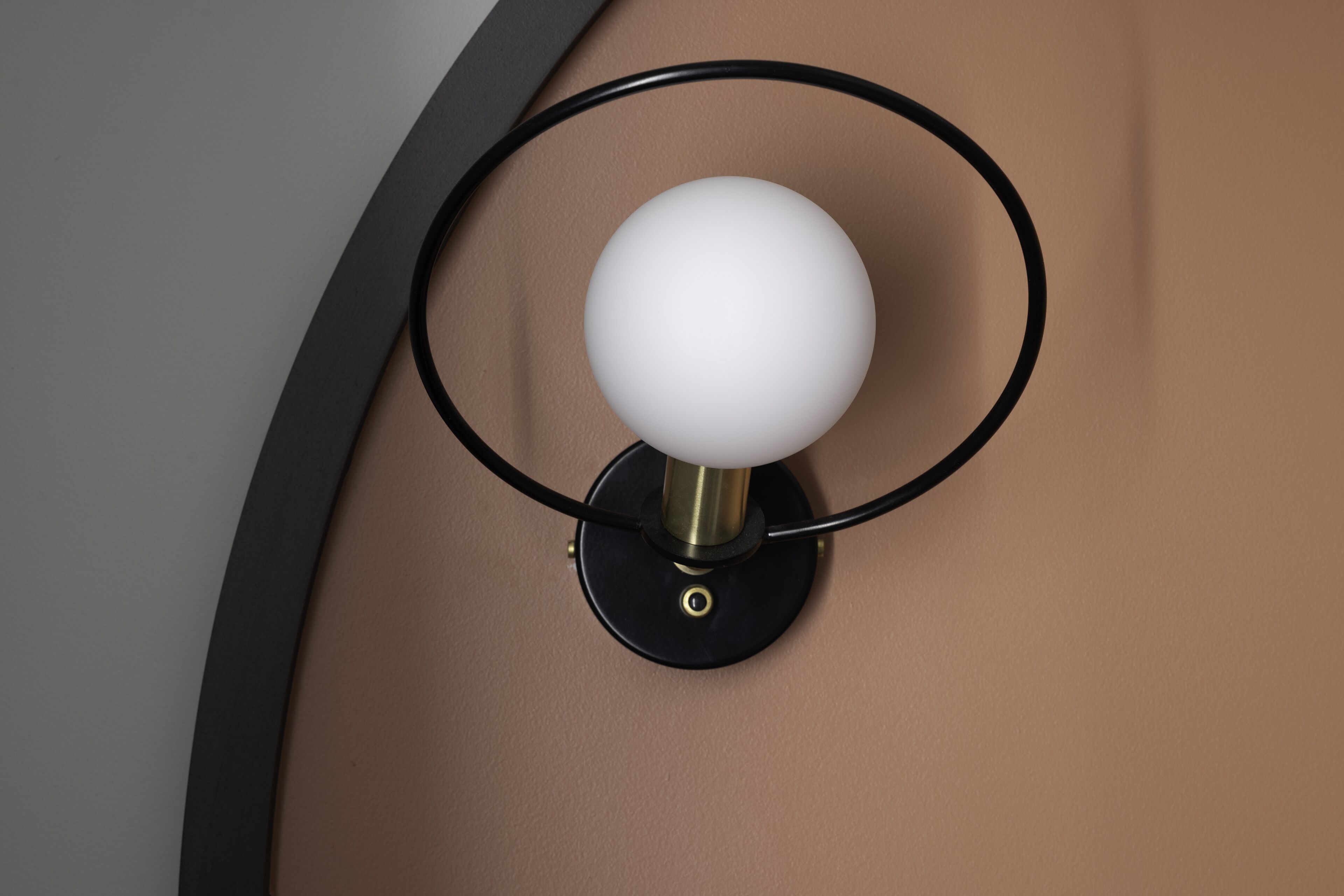 A wall-mounted light fixture with a spherical bulb and a circular base.