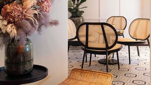A dining area with wicker chairs, a round table, and a vase of dried flowers. - Le Clark Hotel (Paris)