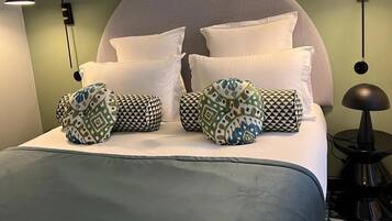A bed with a large, round headboard, multiple pillows, and two wall-mounted lamps.