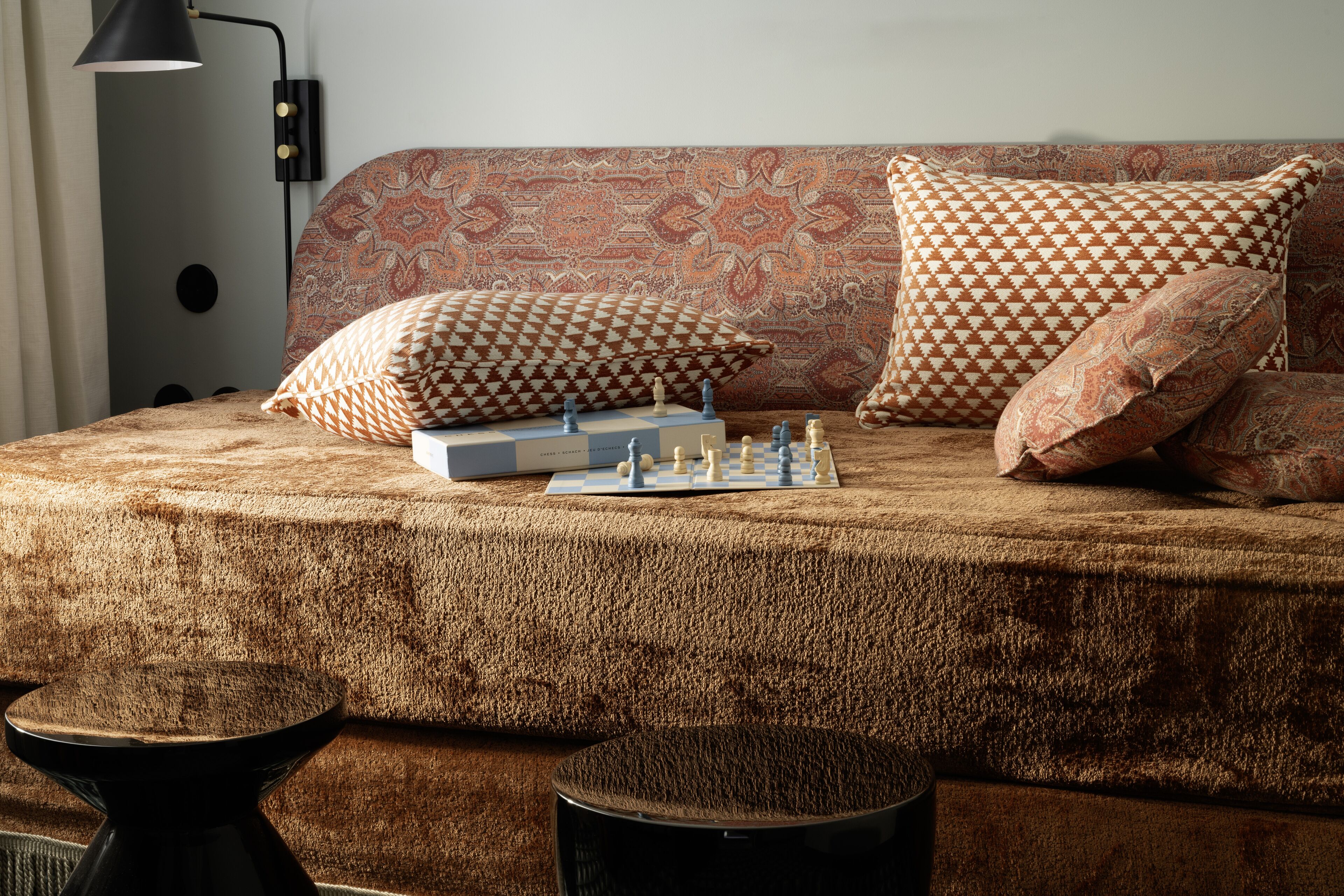 A cozy room with a patterned sofa, a chessboard, and a lamp.
