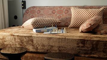 A cozy room with a patterned sofa, a chessboard, and a lamp.