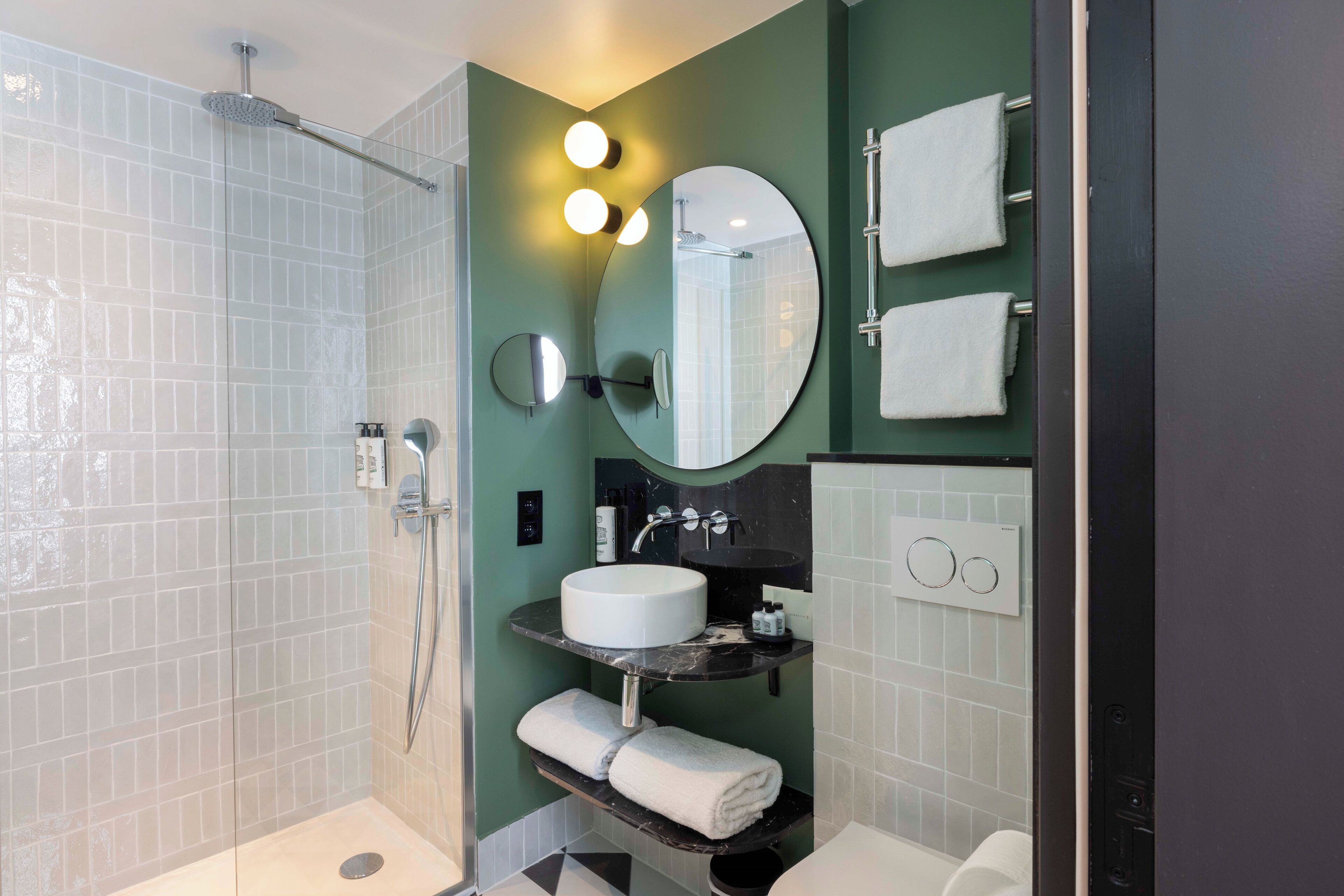 Een moderne badkamer met een douchecabine van glas, een witte wastafel en een grote spiegel.
