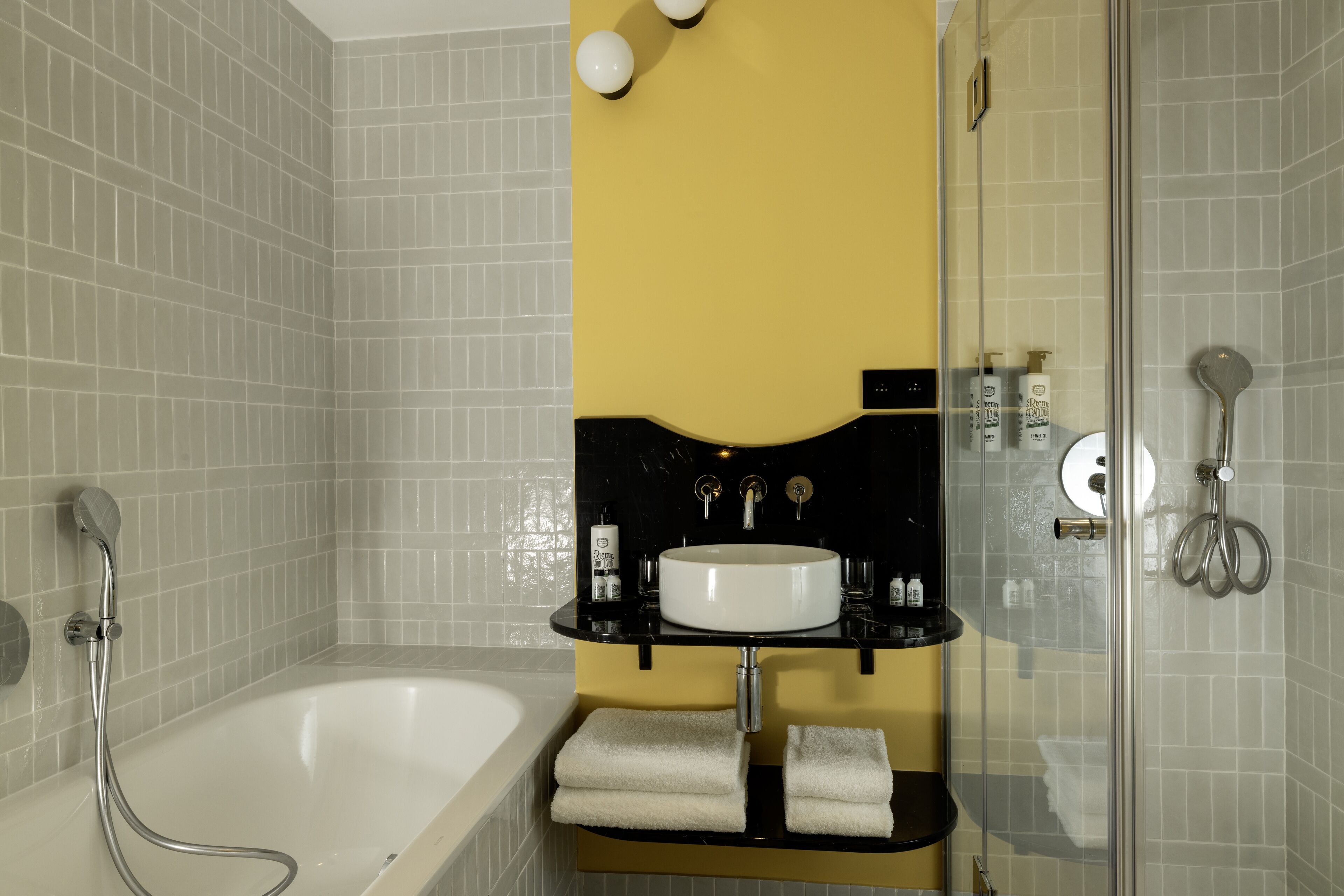 Un baño moderno con bañera, ducha envuelta en vidrio y tocador negro con lavamanos blanco.