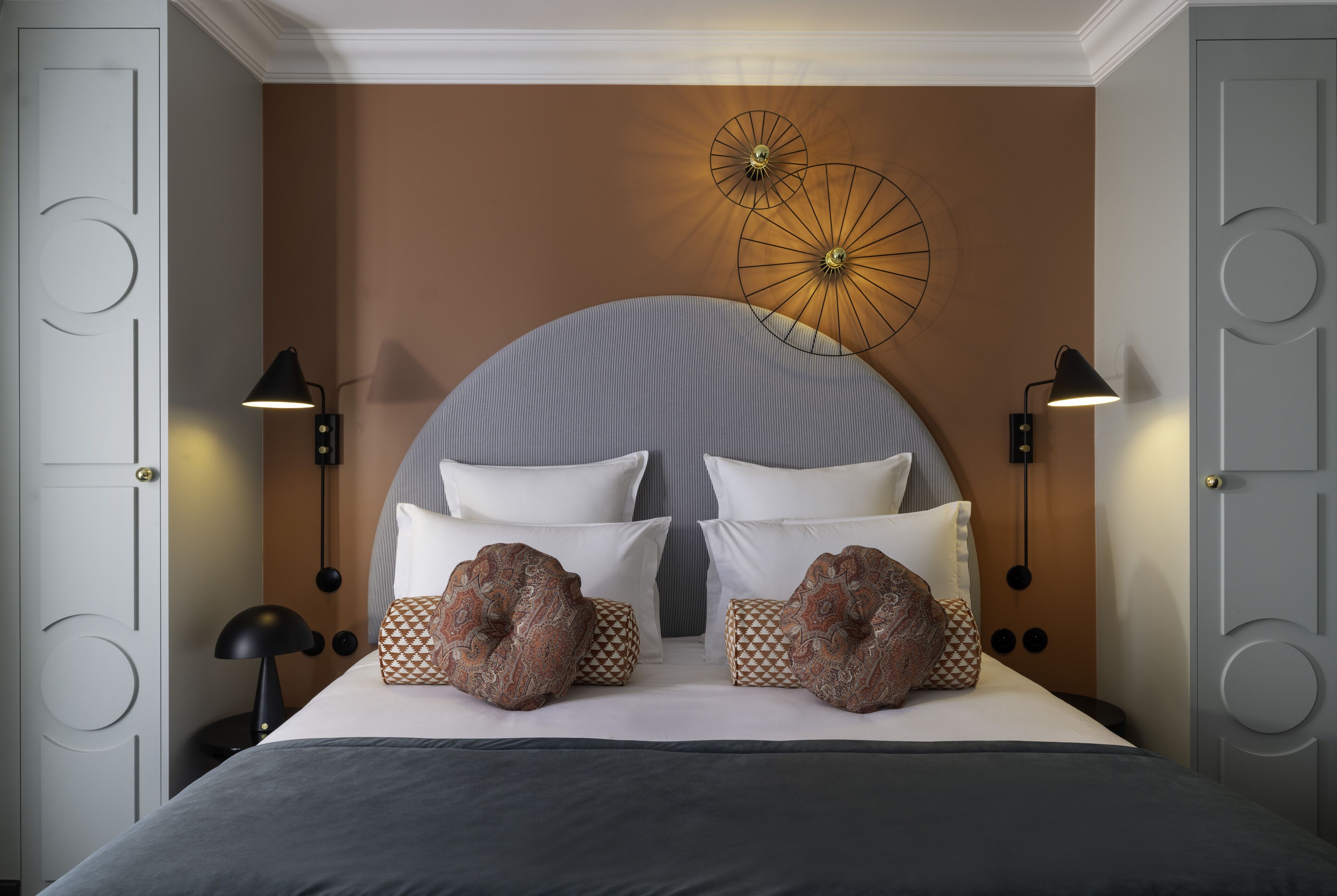 Ein Schlafzimmer mit einem großen Bett, zwei Wandlampen und einer dekorativen Wandgestaltung darüber.