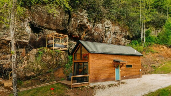 A wooden cabin with a balcony, a door, and a window.