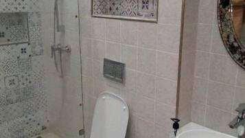 Une salle de bain avec des toilettes, un lavabo et une douche.
