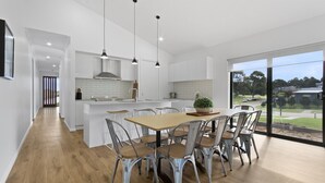 Une cuisine moderne avec des meubles blancs, un îlot central et des luminaires suspendus.
