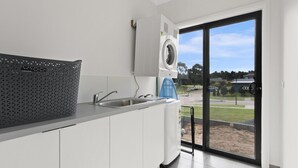 Une cuisine moderne dotée d’un lave-linge encastré, d’une grande fenêtre et offrant une vue sur l’extérieur.
