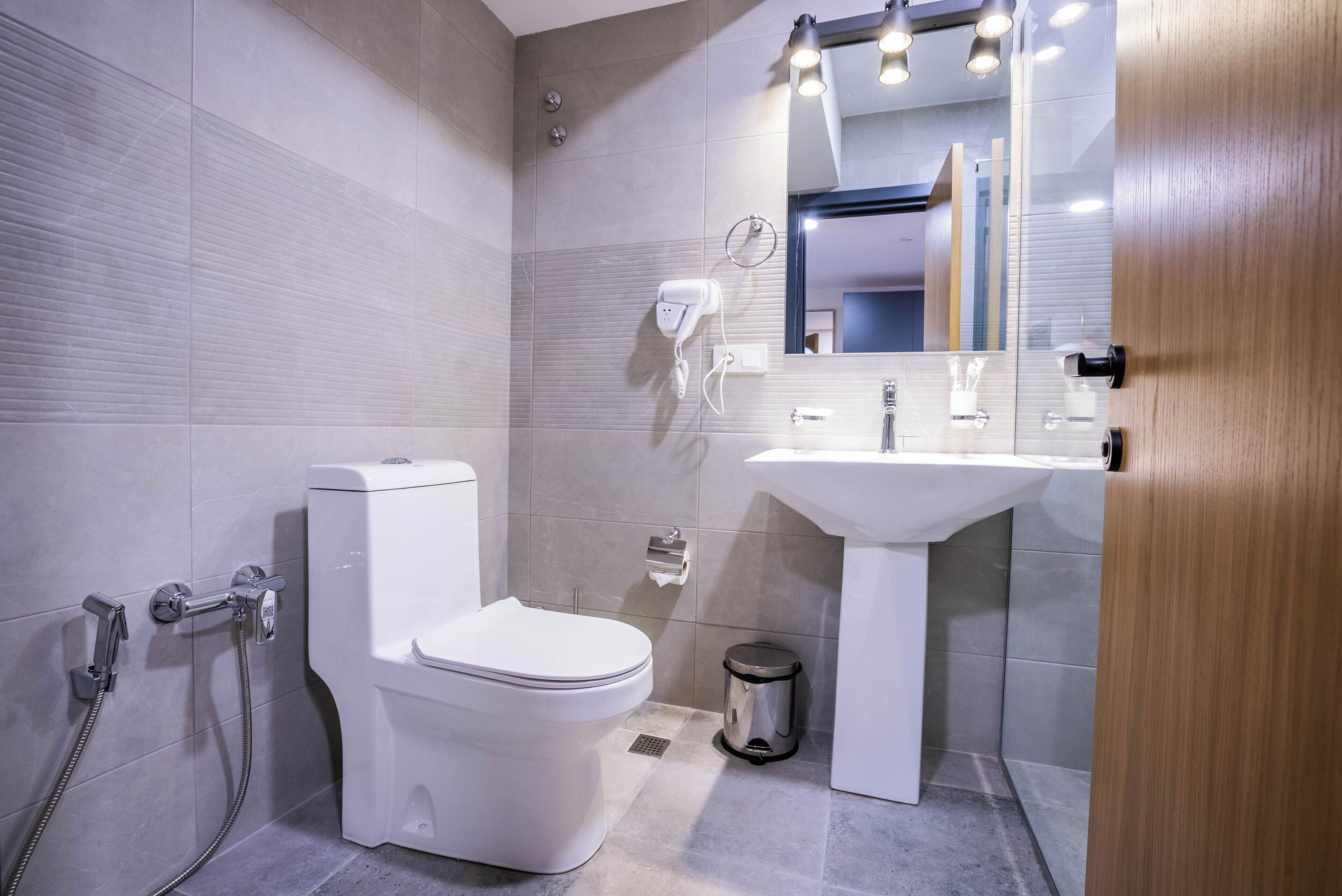 Ein modernes Badezimmer mit Toilette, Dusche, Waschbecken und Spiegel.