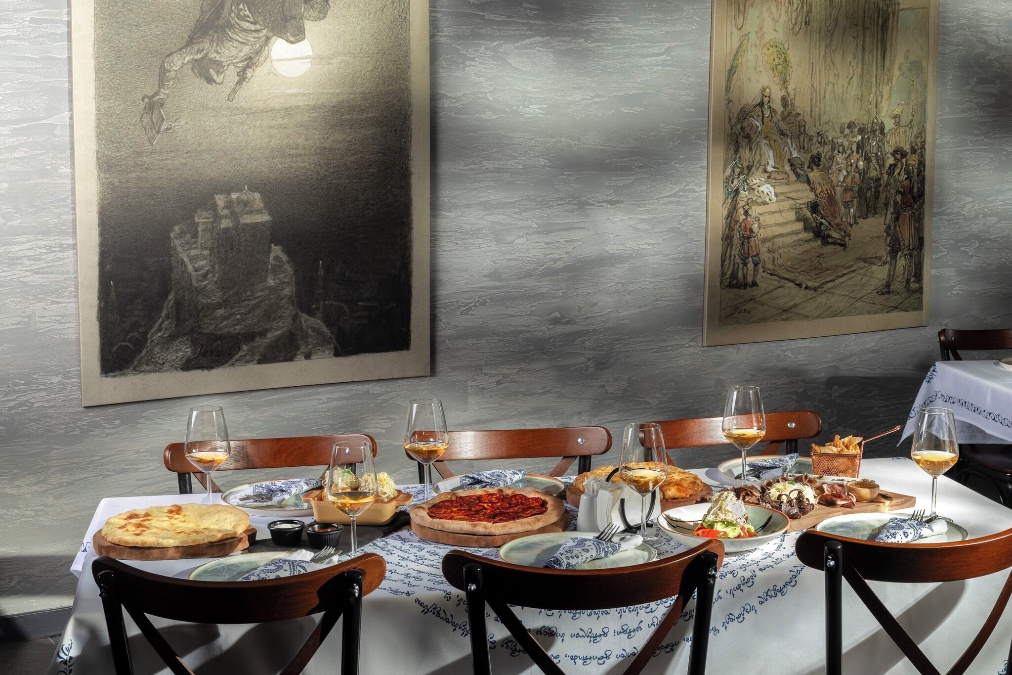 A dining table set with various dishes, glasses, and a candle holder, surrounded by chairs.