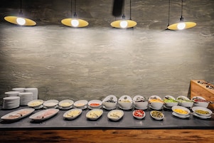 A buffet setup with various food items and plates.