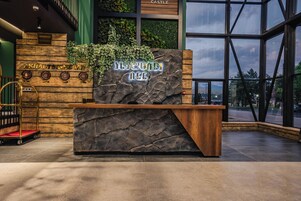 A reception desk with a stone facade and a sign that reads "AKHALTSING W".