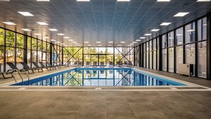 A large indoor swimming pool with clear glass walls, allowing views of the outdoors. - Akhaltsikhe Inn (Akhaltsikhe)