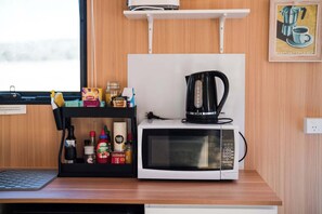 A kitchen with a microwave, kettle, and various condiments. - Hermano Farm Stay by Tiny Away (Turill)