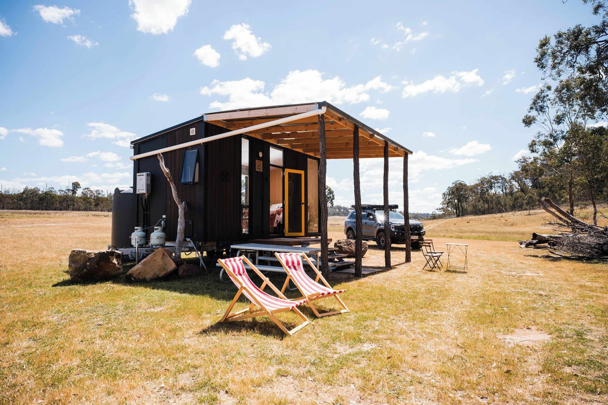 A small cabin with a porch, a truck, and outdoor seating.