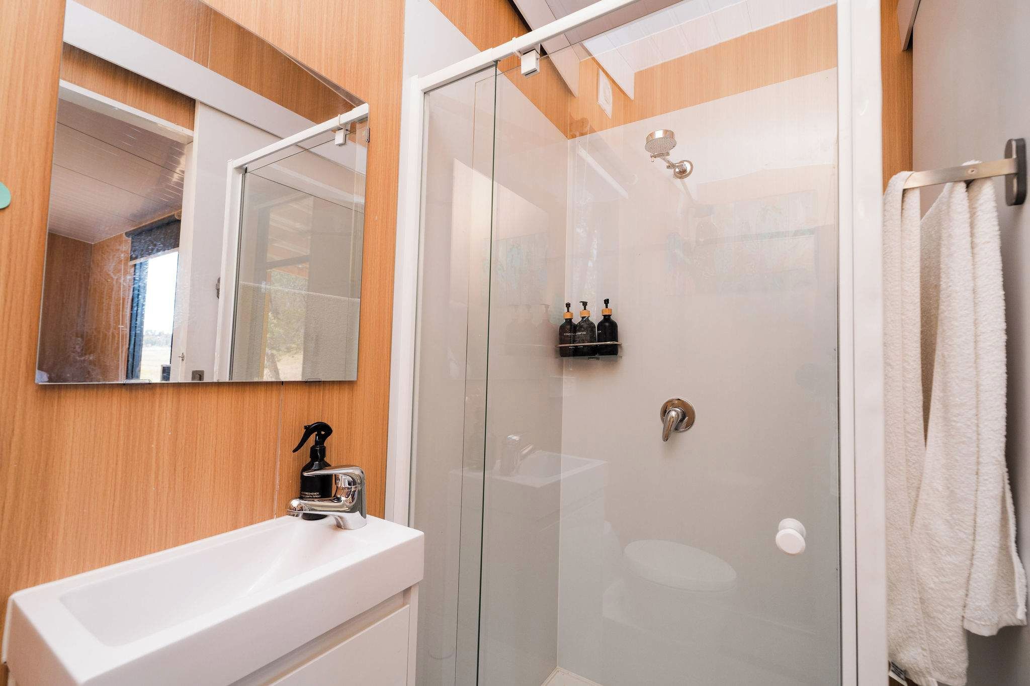A bathroom with a glass-enclosed shower, a white sink with a chrome faucet, and a mirror above the sink.