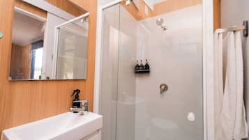 A bathroom with a glass-enclosed shower, a white sink with a chrome faucet, and a mirror above the sink.