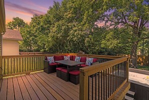 A wooden deck with a built-in seating area featuring red cushions and a table.