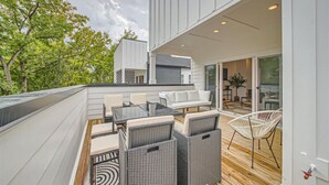 A modern outdoor patio with a dining area, wicker furniture, and a view of the surrounding trees. - 24- Home w/  Rooftop- The Music City Collection (Berry Hill)