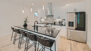 A modern kitchen with a large island, stainless steel appliances, and a minimalist design. - 24- Home w/  Rooftop- The Music City Collection (Berry Hill)