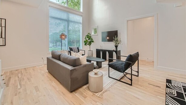 A modern living room with a grey sofa, a black chair, a coffee table, and a TV mounted on the wall. - 24- Home w/  Rooftop- The Music City Collection (Berry Hill)