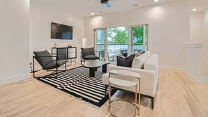 A modern living room with a sofa, chairs, a coffee table, and a TV mounted on the wall.