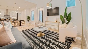 A modern living room with a sofa, coffee table, and a TV mounted on the wall.