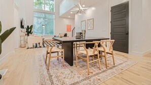 A modern kitchen with a central island, wooden chairs, and a patterned rug.