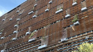 A modern building with a unique facade featuring a grid of wooden slats and air conditioning units. - Sophisticated Lakeview Apt + Parking (Canberra)
