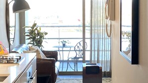 A modern kitchen with a built-in oven and a dining area with a sofa and a small table. - Sophisticated Lakeview Apt + Parking (Canberra)