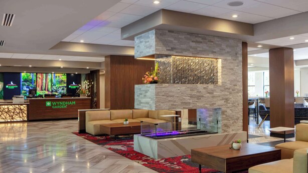 Un lobby moderno con mostrador de recepción, zona de estar y una pared decorativa con chimenea.