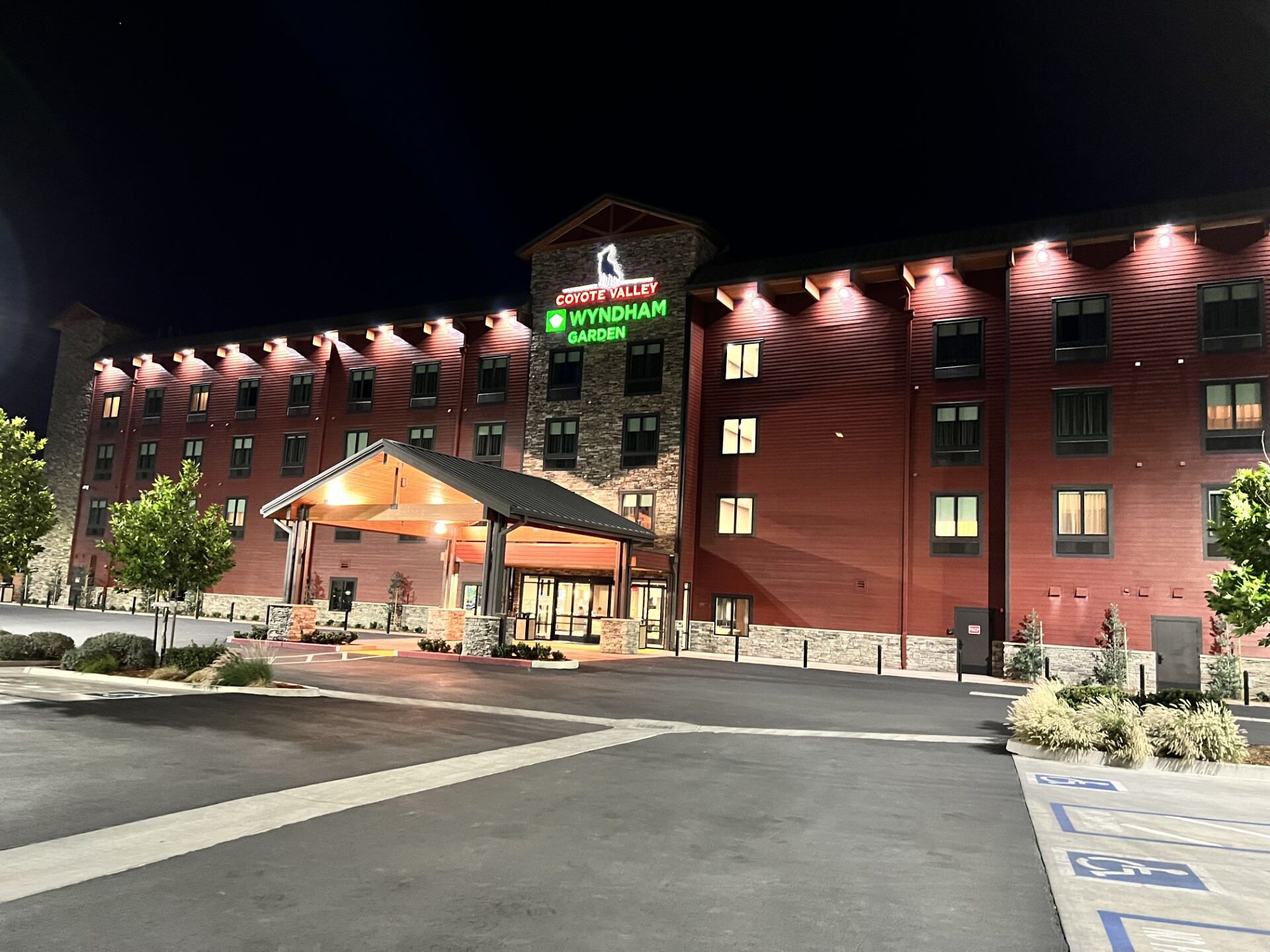 A hotel with a prominent 'Coyote Valley Wyndham Garden' sign, a covered entrance, and a parking lot with handicapped accessibility.