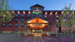 Entrada de hotel con un corredor cubierto, un cartel de 'Coyote Valley Wyndham Garden' y un estacionamiento.