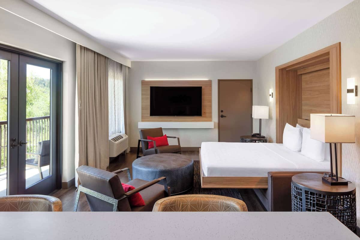 Habitación de hotel con cama, televisión, escritorio, silla y ventana.