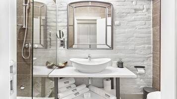 A modern bathroom with a white sink, glass shower enclosure, and a mirror above the sink.