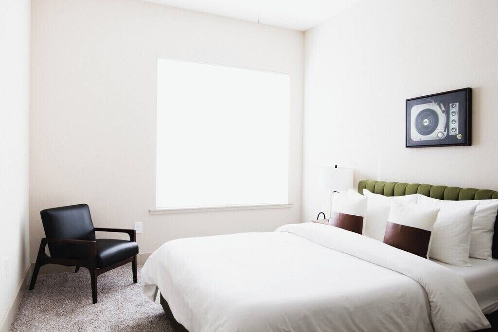 Una habitación de hotel con una cama, una silla, una ventana y un altavoz en la pared.