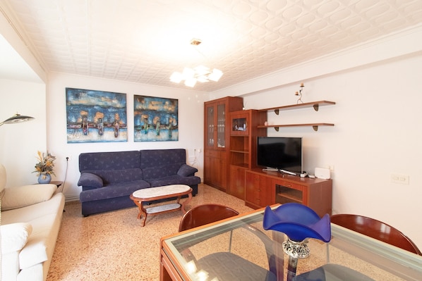 A living room with a sofa, coffee table, TV stand, and artwork on the wall.