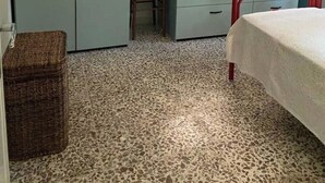 Ein Schlafzimmer mit einem Bett, einem Schreibtisch, einem Stuhl, einem Kleiderschrank und einem Fenster.