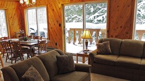 A cozy cabin interior with a wooden dining area, a sofa, and a lamp.