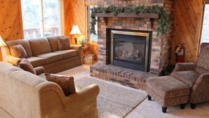 A cozy living room with a fireplace, wooden walls, and comfortable seating.